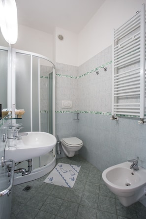 A bathroom with a white sink, a bidet, a toilet, and a glass shower enclosure. - Hotel Club Misano (Misano Adriatico)