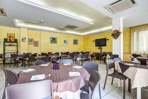 A conference room with multiple tables and chairs, air conditioning units, and wall-mounted decorations. - Hotel Club Misano (Misano Adriatico)
