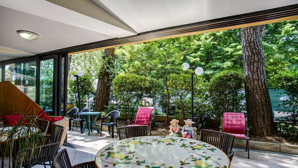 A modern outdoor seating area with wicker chairs and a round table with a floral design. - Hotel Club Misano (Misano Adriatico)