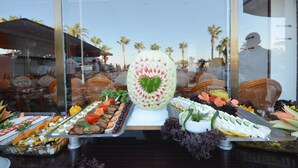 Un bufé con diversos alimentos y una sandía como pieza central con diseño de corazón.