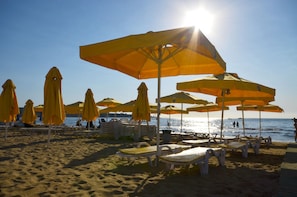 A beach with yellow umbrellas and white lounge chairs. - Admiral Hotel (Erdemli)