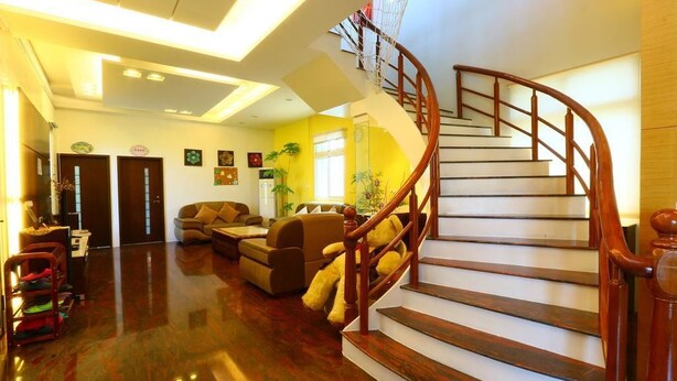 Un vestíbulo espacioso con piso de madera pulida, una escalera curva y una zona de estar con sofás y una mesa de centro.