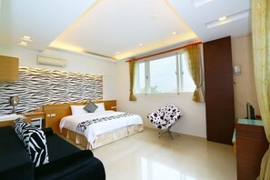 A modern hotel room with a zebra-patterned headboard, a bed with a white and black patterned bedspread, a round chair, and a window with curtains. - Dream Villa (Dongshan)