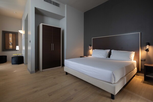 A modern bedroom with a large bed, a wardrobe, and a desk with a lamp. - Art Hotel Olympic (Turin)