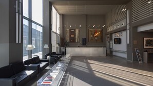 A modern lobby with a reception desk, seating area, and large windows. - Art Hotel Olympic (Turin)