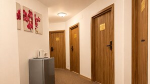 A hallway with wooden doors, a refrigerator, and a coffee machine. - Monte Carlo Palace Rooms  (Bucharest)