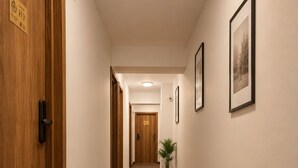 A hallway with wooden doors, a potted plant, and framed pictures on the walls. - Monte Carlo Palace Rooms  (Bucharest)
