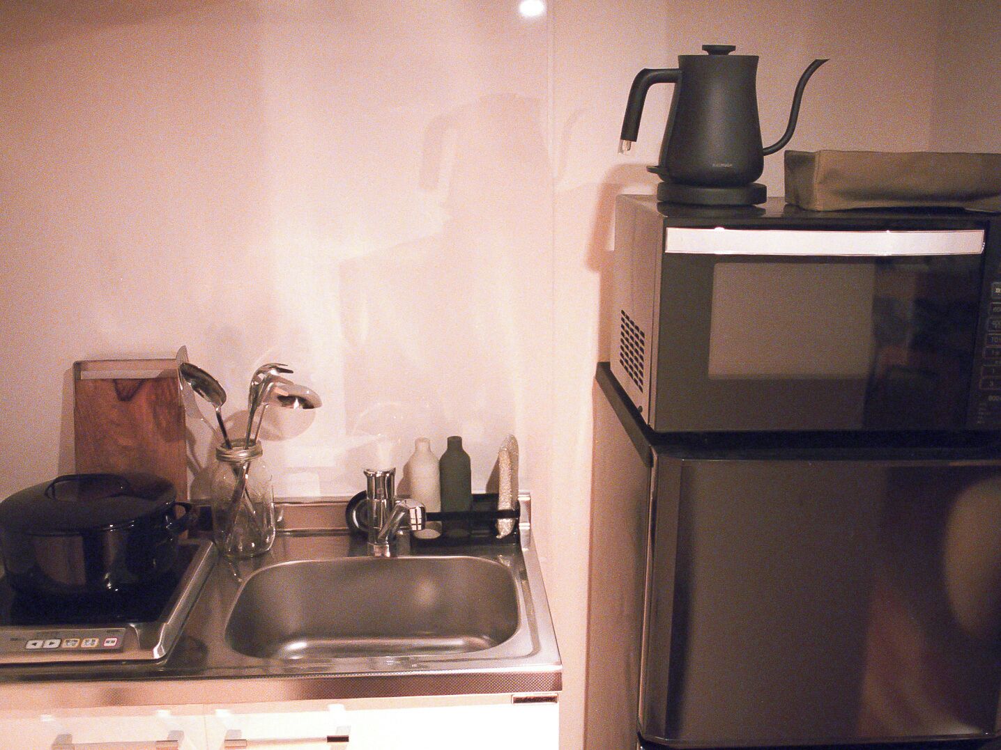 A kitchen with a sink, a coffee maker, a kettle, and a microwave.