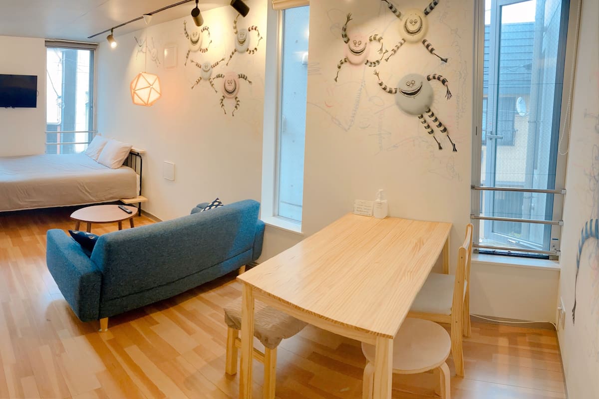 Une chambre moderne avec un lit, un canapé bleu, une table en bois et un mur décoré d’œuvres d’art.