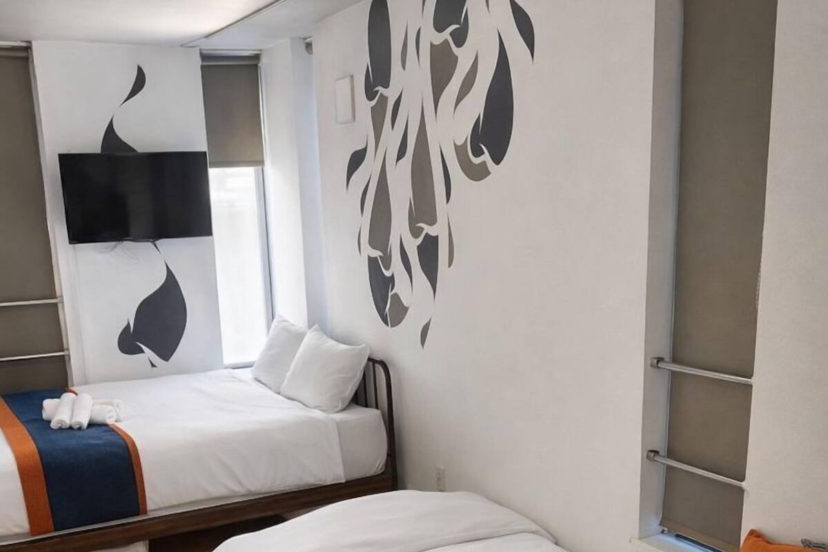 Une chambre d’hôtel avec deux lits, une table ronde en bois et une grande fenêtre.