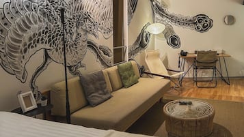 A modern room with a large wall mural, a sofa, a small table, and a chair.