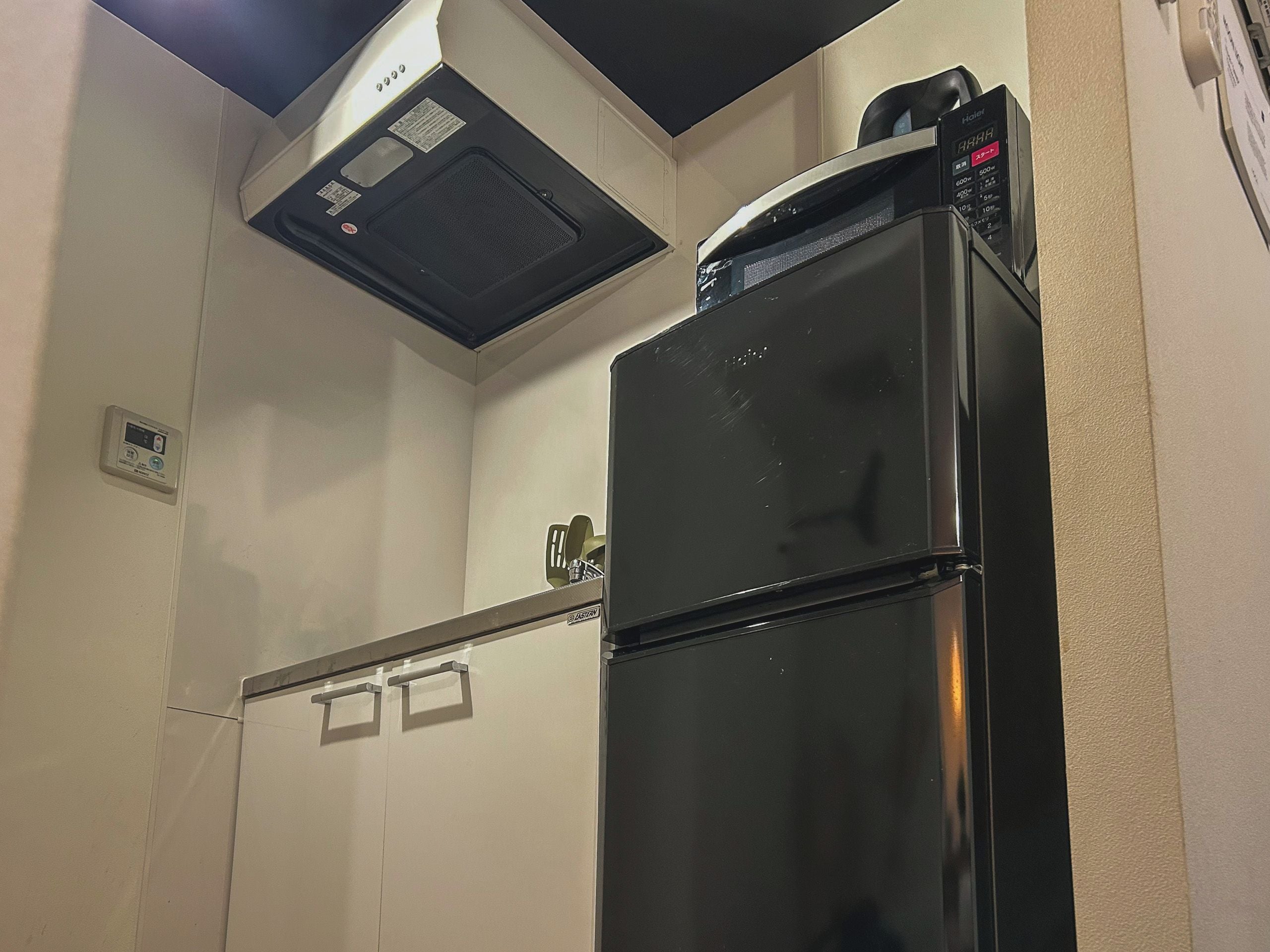 A compact kitchen with a black refrigerator, a microwave, and a small cabinet.