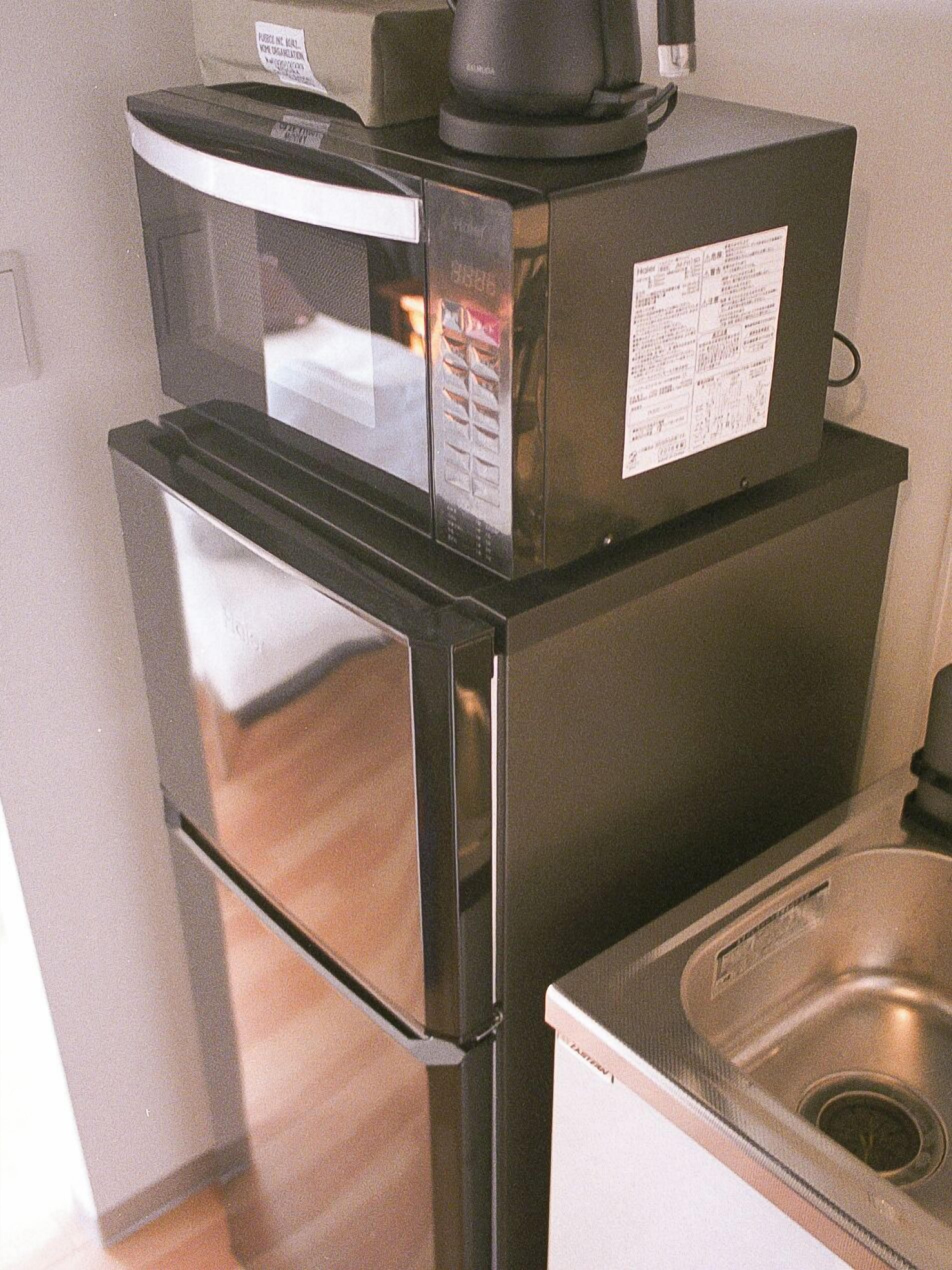 A compact kitchen with a refrigerator, microwave, and a sink.