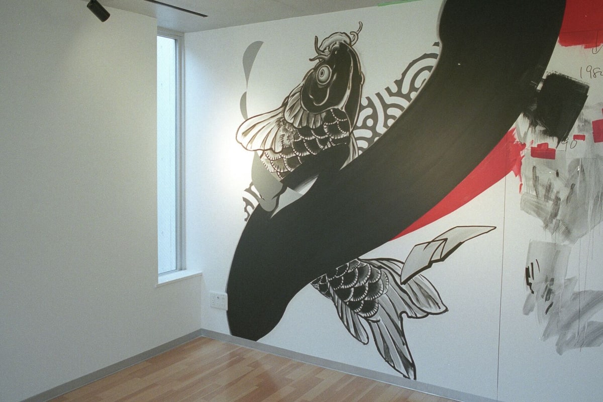 Une pièce dont un grand mur est décoré d’une fresque représentant un poisson et d’œuvres d’art abstrait.