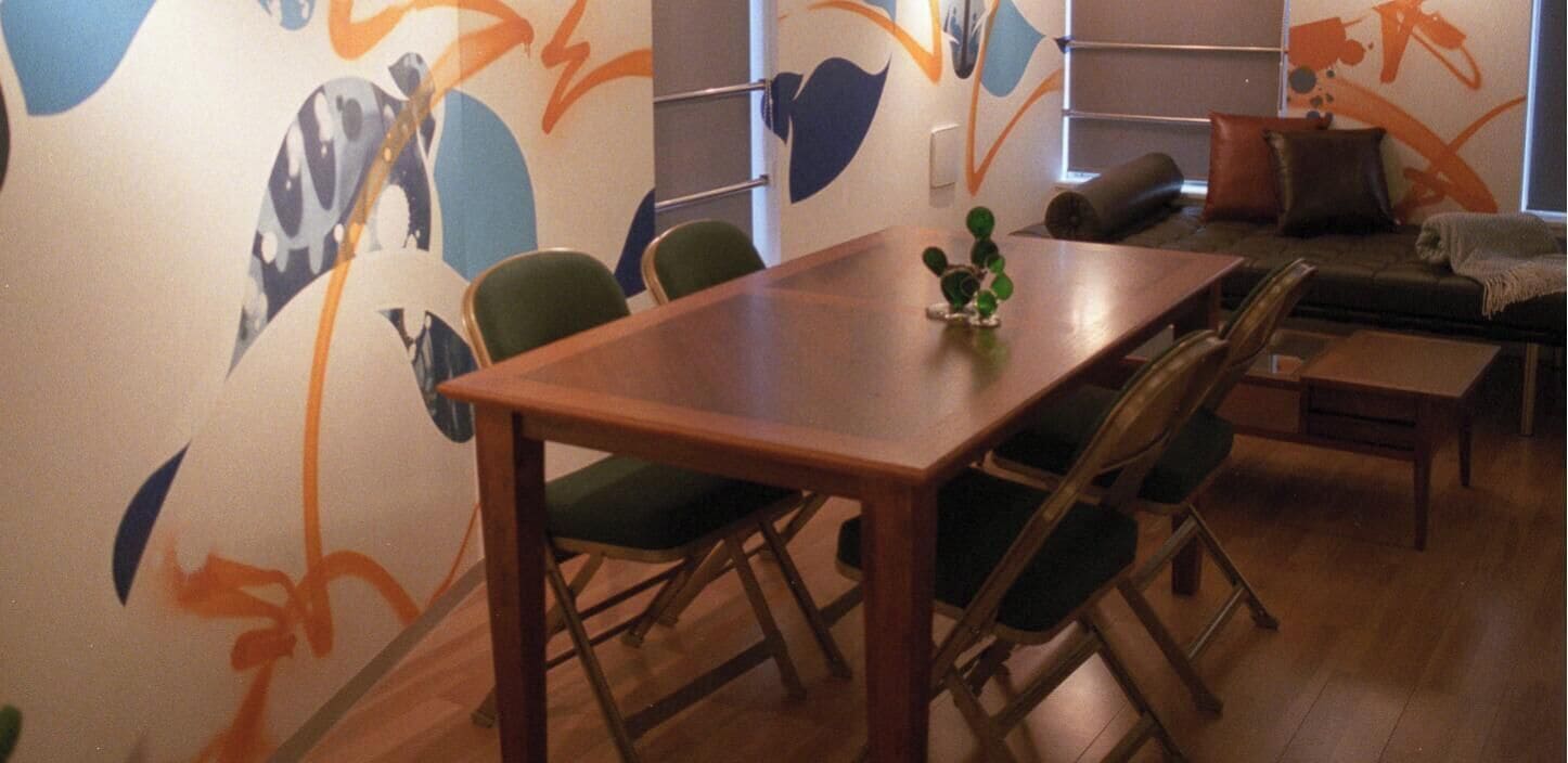 A dining area with a wooden table and chairs, a sofa, and a decorative plant.