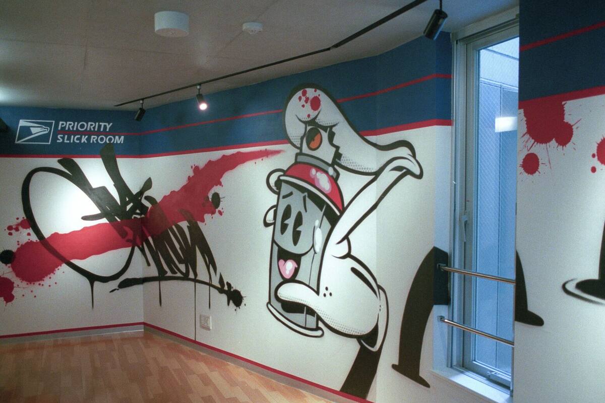 Une pièce décorée d’une fresque murale représentant un personnage de dessin animé, d’un panneau indiquant qu’il s’agit d’une salle réservée aux personnes devant être prises en charge en priorité, et d’une fenêtre avec des stores.