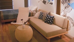 Un salon chaleureux avec un canapé, des coussins, une petite table ronde et un lampadaire à pied en osier.