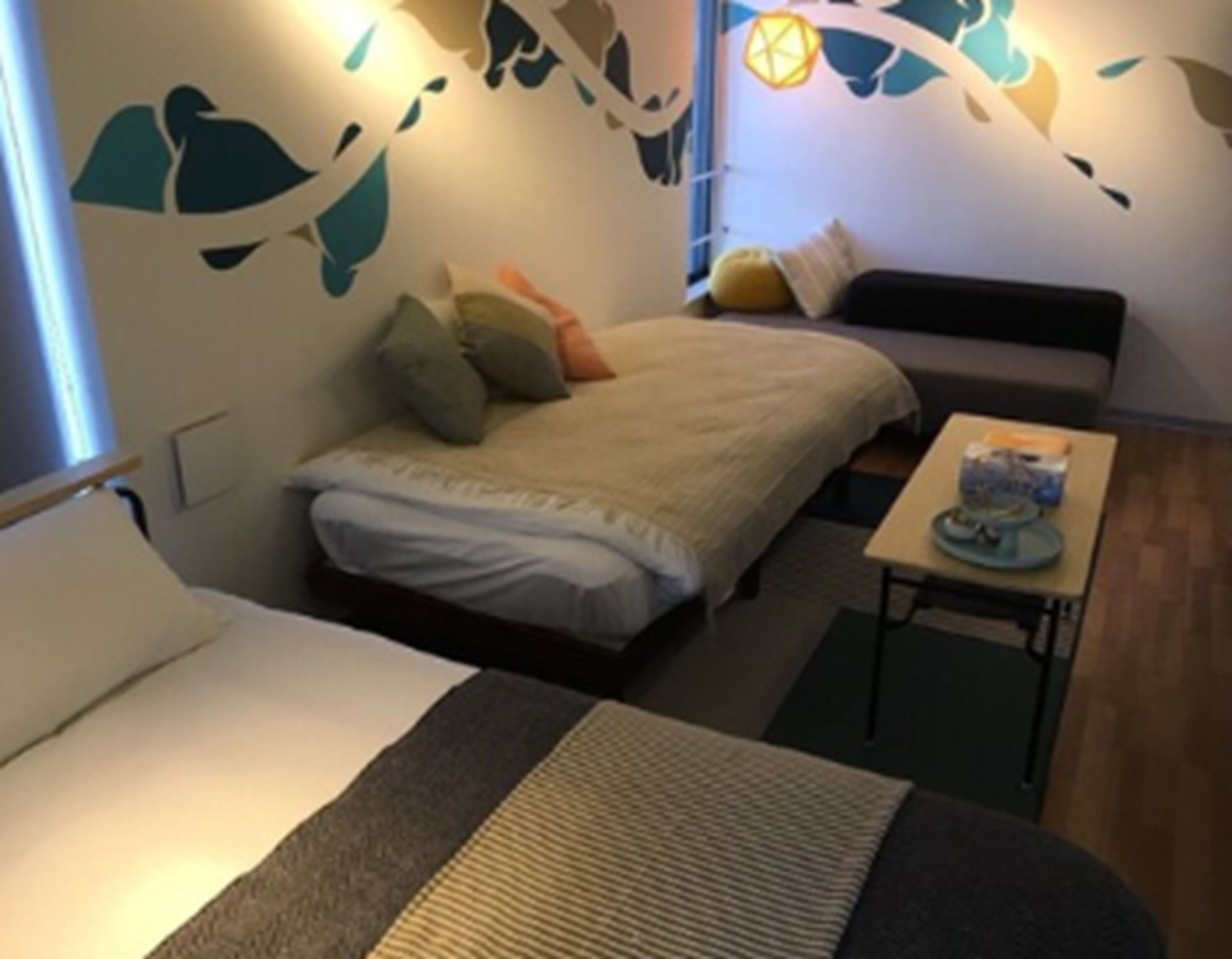 A small, cozy room with a bed, a sofa, and a small table with a lamp.