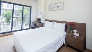 A hotel room with a large bed, a desk with a lamp, and a view of the outside balcony. - Tigon Hotel (Hanoi)