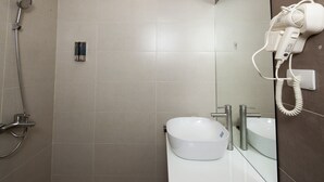 A bathroom with a white sink, a mirror, a handheld hair dryer, and a shower head. - Tigon Hotel (Hanoi)
