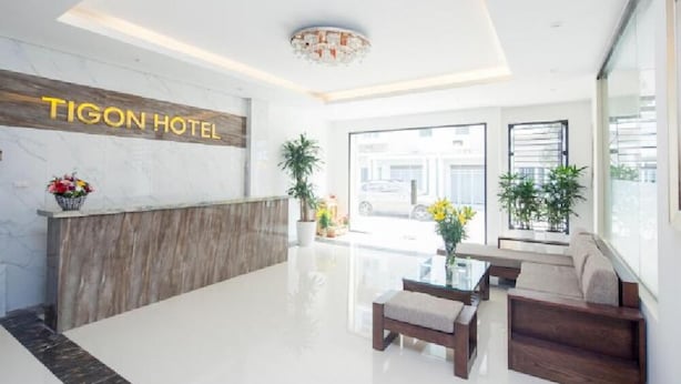 A modern hotel lobby with a reception desk, seating area, and large windows. - Tigon Hotel (Hanoi)