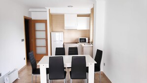A compact kitchen with white cabinets, a microwave, and a refrigerator. - Apartamentos Revolta Sanxenxo 3000 (Sanxenxo)