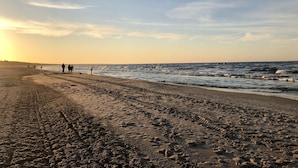 A beach with footprints and people walking along the shore. - Upstalsboom Trassenheide (Trassenheide)