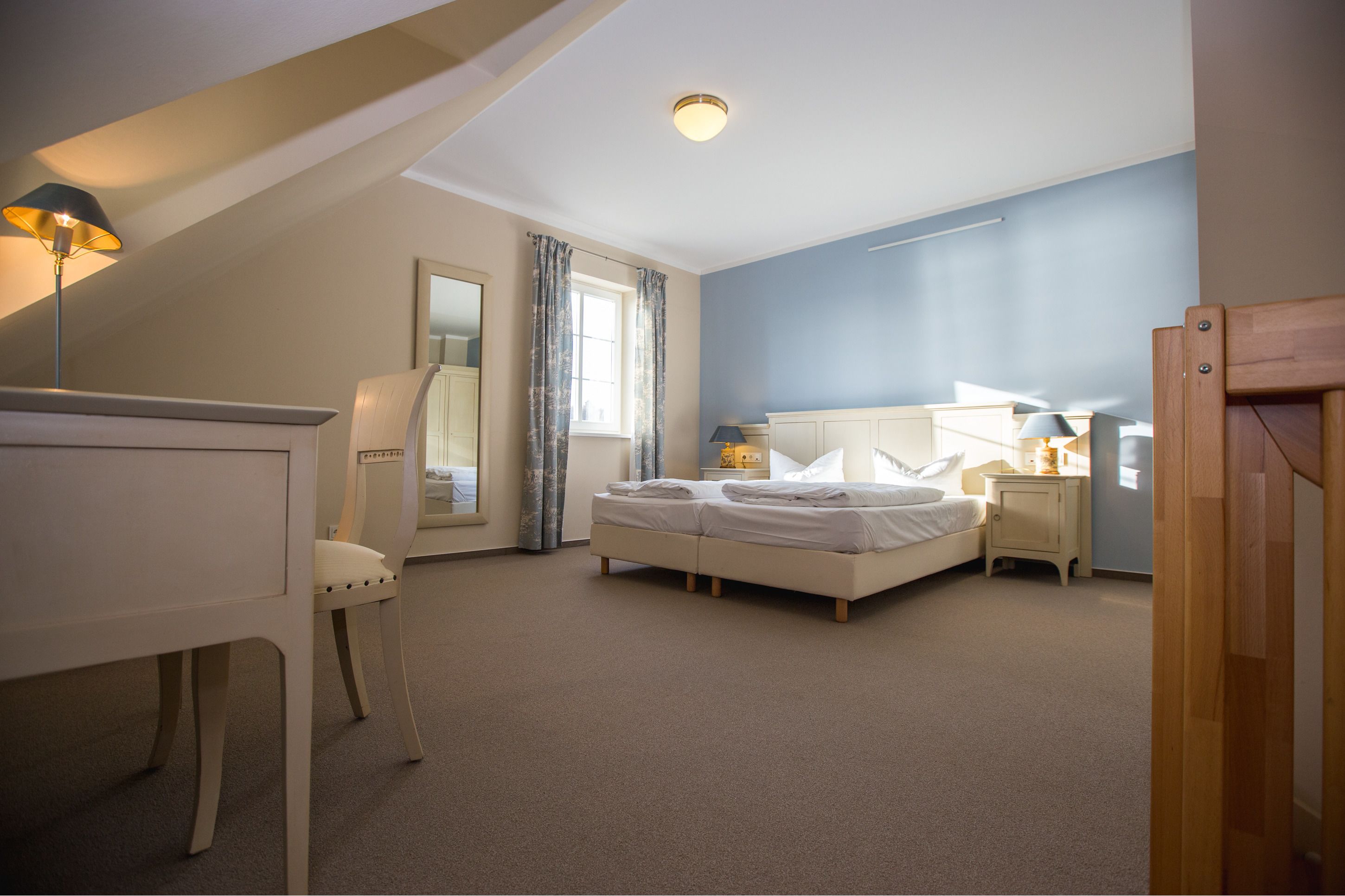 A bedroom with a bed, bedside table, lamp, and a chair.