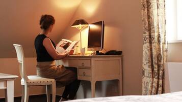 A hotel room with a desk, chair, and a lamp.
