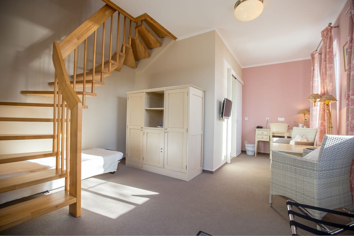 Une chambre avec un escalier en bois, une armoire, un lit, un bureau et une chaise.