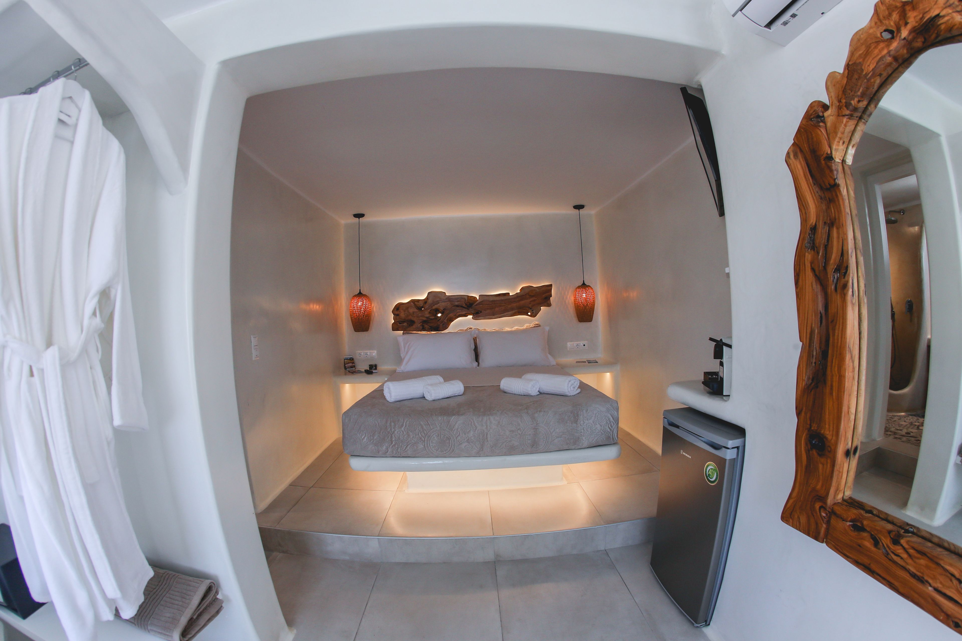 A modern bedroom with a bed, bedside lamps, and a mirror.