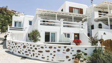 A white building with a stone facade, balconies, and potted plants.