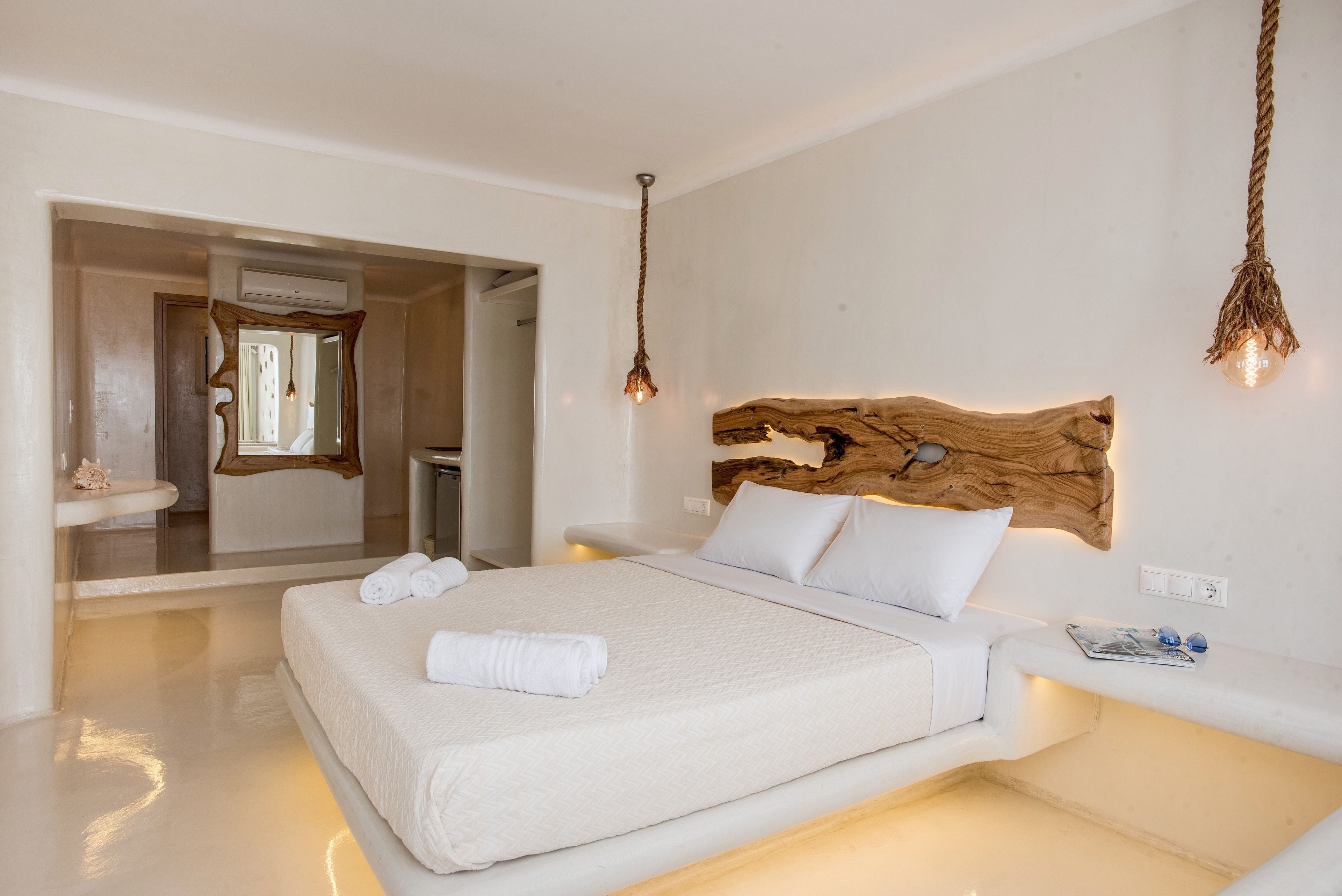 A modern bedroom with a large bed, a wooden headboard, and a hanging light fixture.
