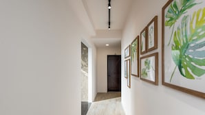 Un pasillo con impresiones botánicas enmarcadas en la pared, suelo de madera y una puerta al final.