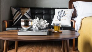 Una sala moderna con una mesa de centro de madera, un sofá con cojines estampados y un cactus decorativo en la pared.