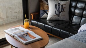 Una sala de estar moderna con un sofá de cuero, una mesa de centro de madera con una revista, y un vaso de jugo de naranja.