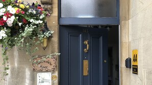 A dark blue door with the number 143, a sign indicating 'BIGHAM' and 'GUEST ACCOMMODATION', and a yellow sign with 'AA' and three stars.