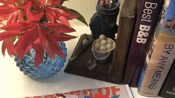 A desk with a blue glass vase containing red foliage, a small figurine, a book titled 'Britain's Best B&B', and a magazine cover with '2020' and 'B&B' visible.