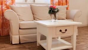 A beige sofa with a white side table and a vase of flowers. - Café Wildau - Pension am Werbellinkanal (Schorfheide)