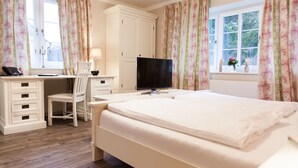 A bedroom with a bed, a desk, a chair, a television, and a window with curtains. - Café Wildau - Pension am Werbellinkanal (Schorfheide)