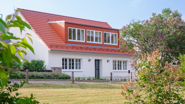 A white house with a red roof, a front porch, and a small garden. - Café Wildau - Pension am Werbellinkanal (Schorfheide)