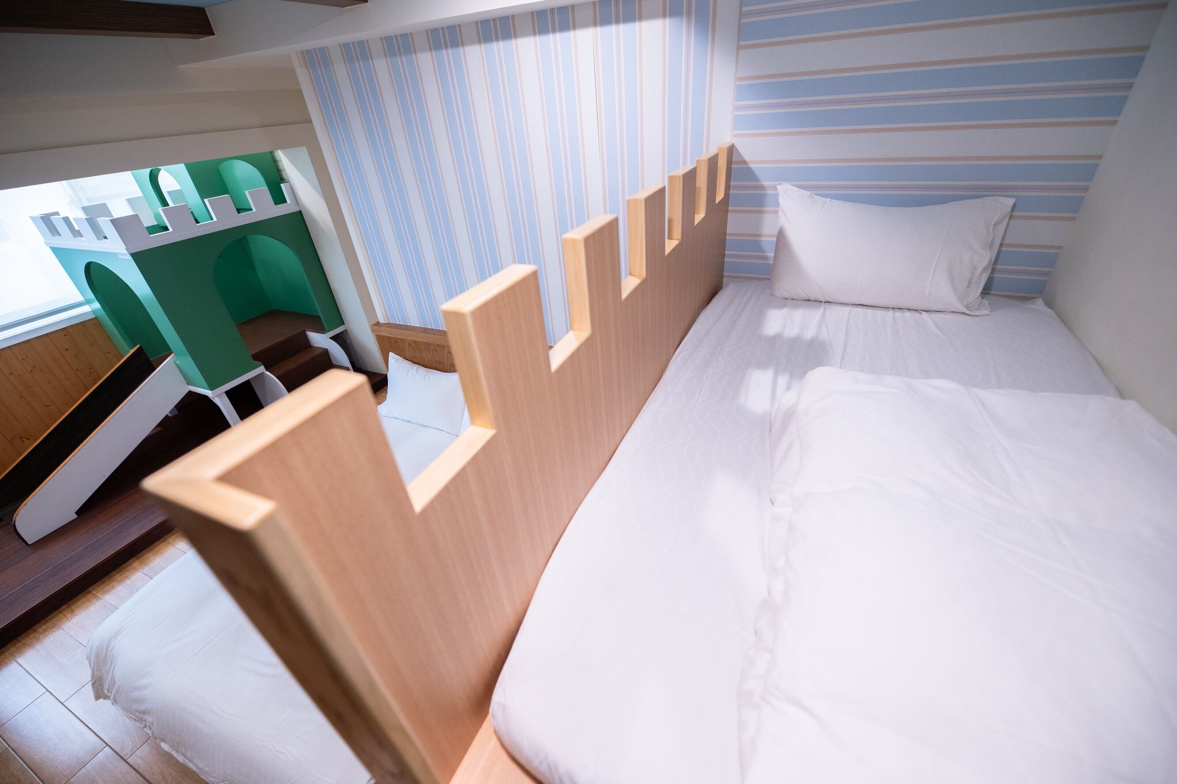A bedroom with a wooden bed, a green desk, and a striped wall.