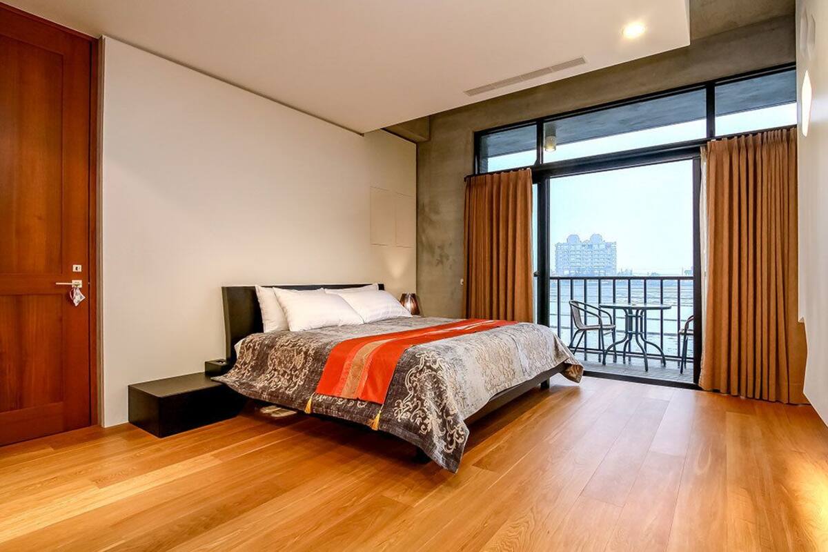 Une chambre moderne avec un grand lit, un balcon offrant une belle vue et un plancher en bois.