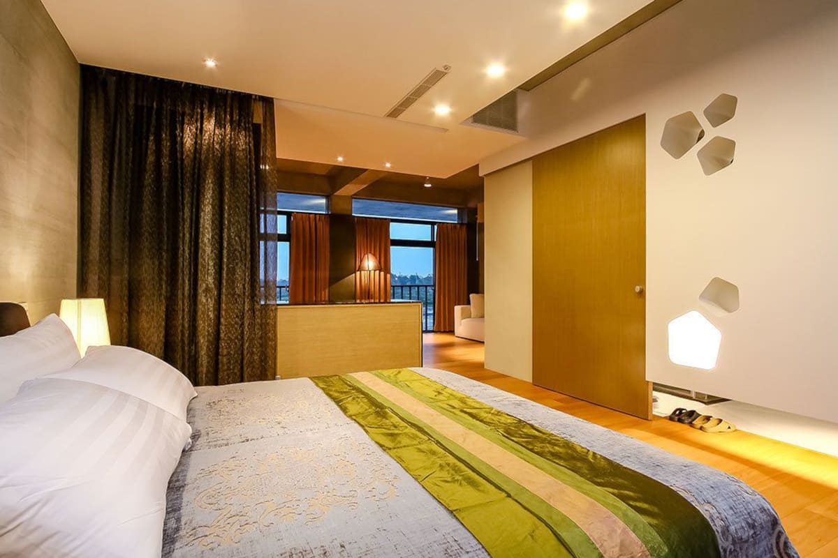 Une chambre d’hôtel moderne avec un grand lit, une vue sur l’extérieur et un balcon.