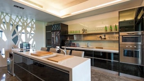 A modern kitchen with a central island, stainless steel appliances, and a variety of bottles on the upper shelf. - Hiten B&B (Wujie)