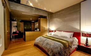 A modern bedroom with a large bed, a walk-in closet, and a separate sitting area.
