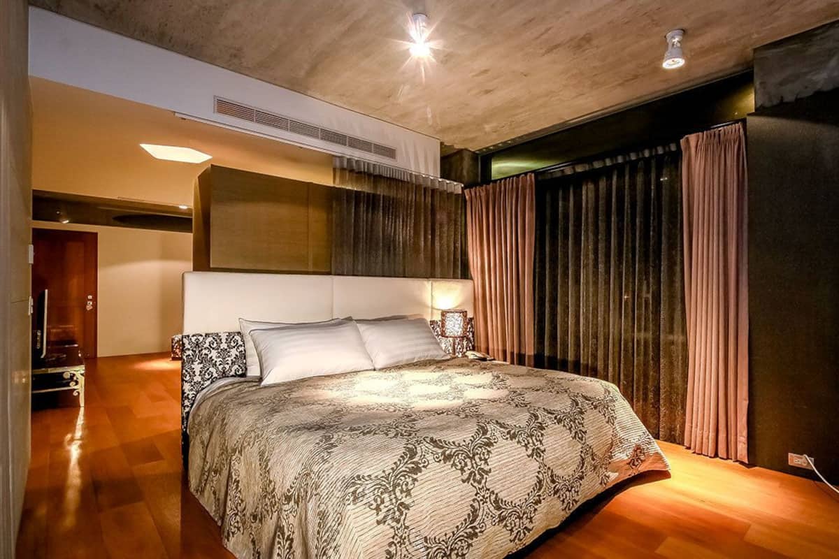 Une chambre moderne avec un grand lit, un plancher en bois et une grande fenêtre avec des rideaux.