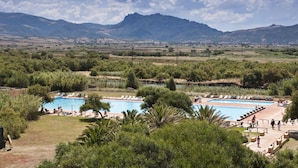 Un complexe hôtelier doté de deux piscines, entouré d’une végétation luxuriante et avec des montagnes en toile de fond.