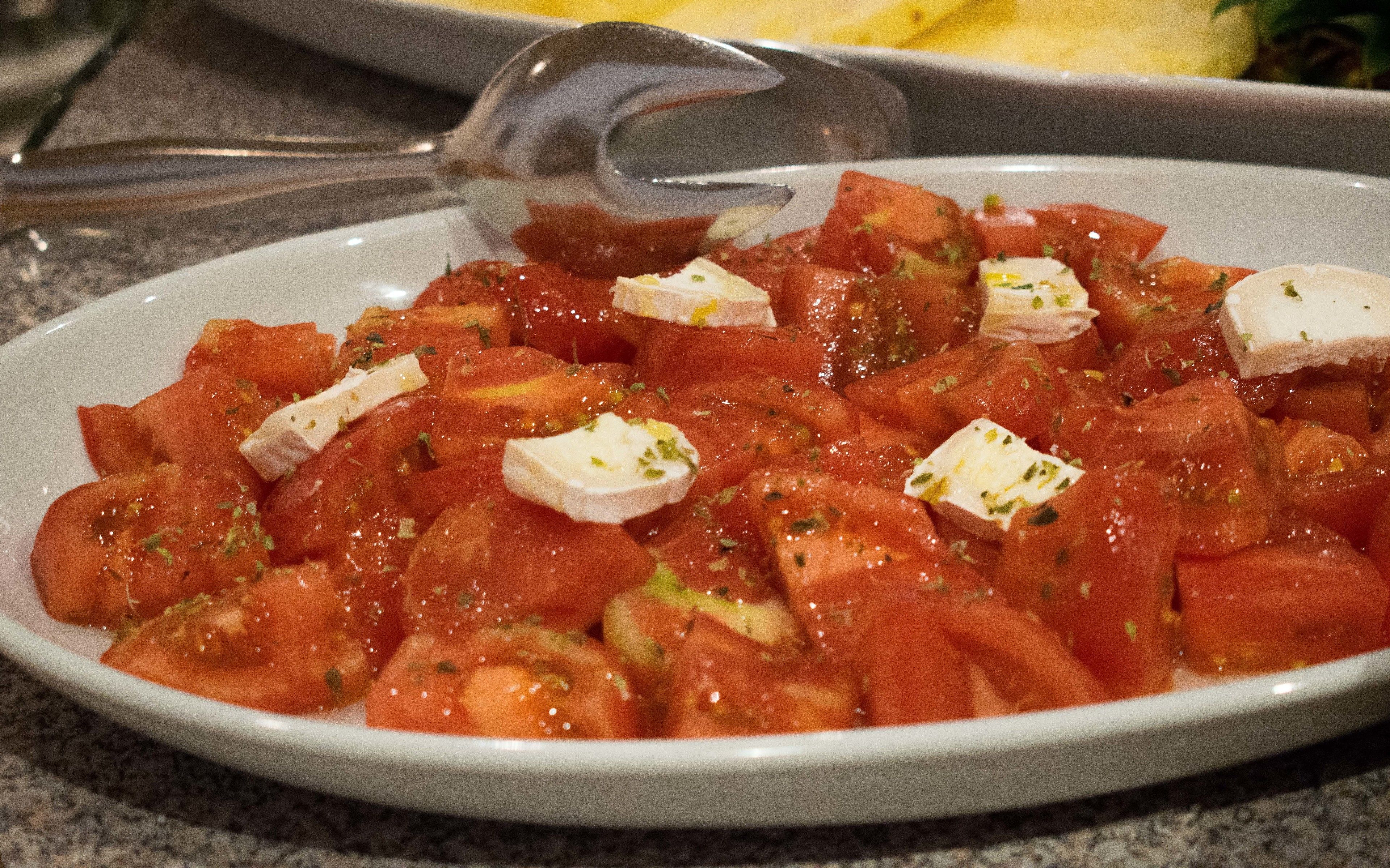 Un plato de tomates picados con queso y hierbas.