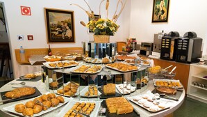 Un bufé con diversos pasteles y postres, una estación de café y un arreglo floral.